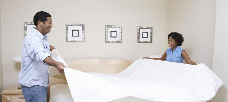 Couple making bed in modern bedroom