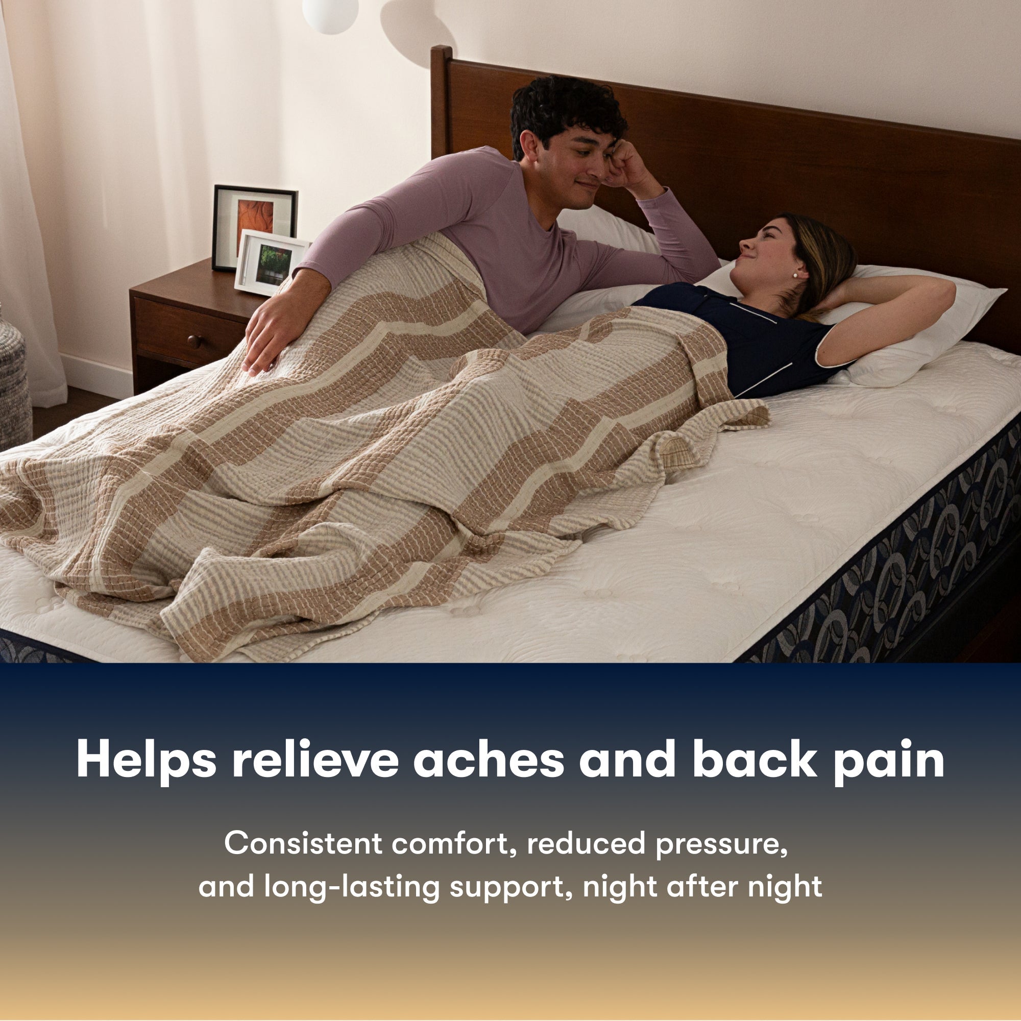 Couple lying in bed on a Serta Perfect Sleeper firm mattress under a striped blanket with text about back pain relief.