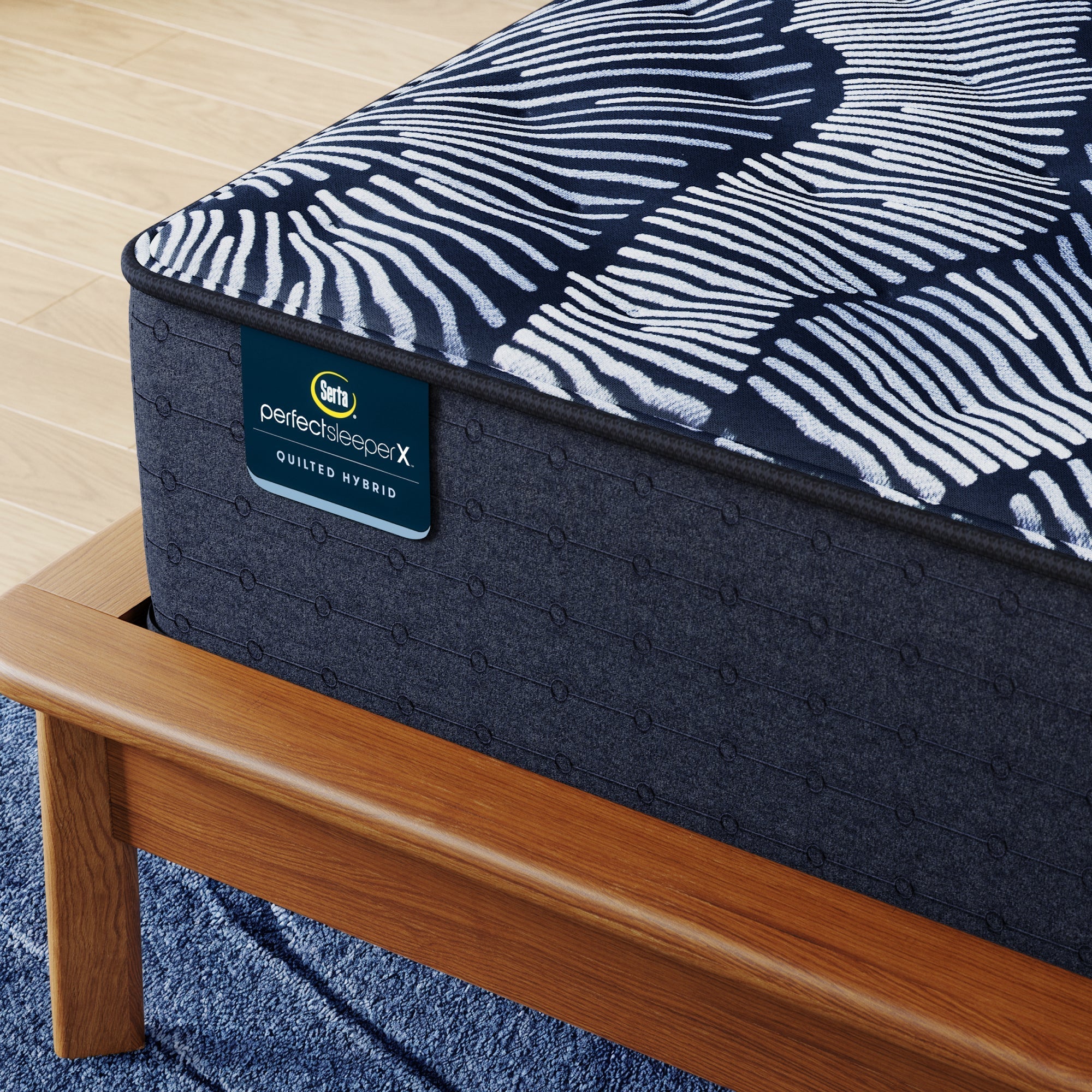 Corner of Perfect Sleeper X Quilted Hybrid Excelled Plush Mattress sitting in a brown bedframe || feel: Enhanced Plush || level: Level 1