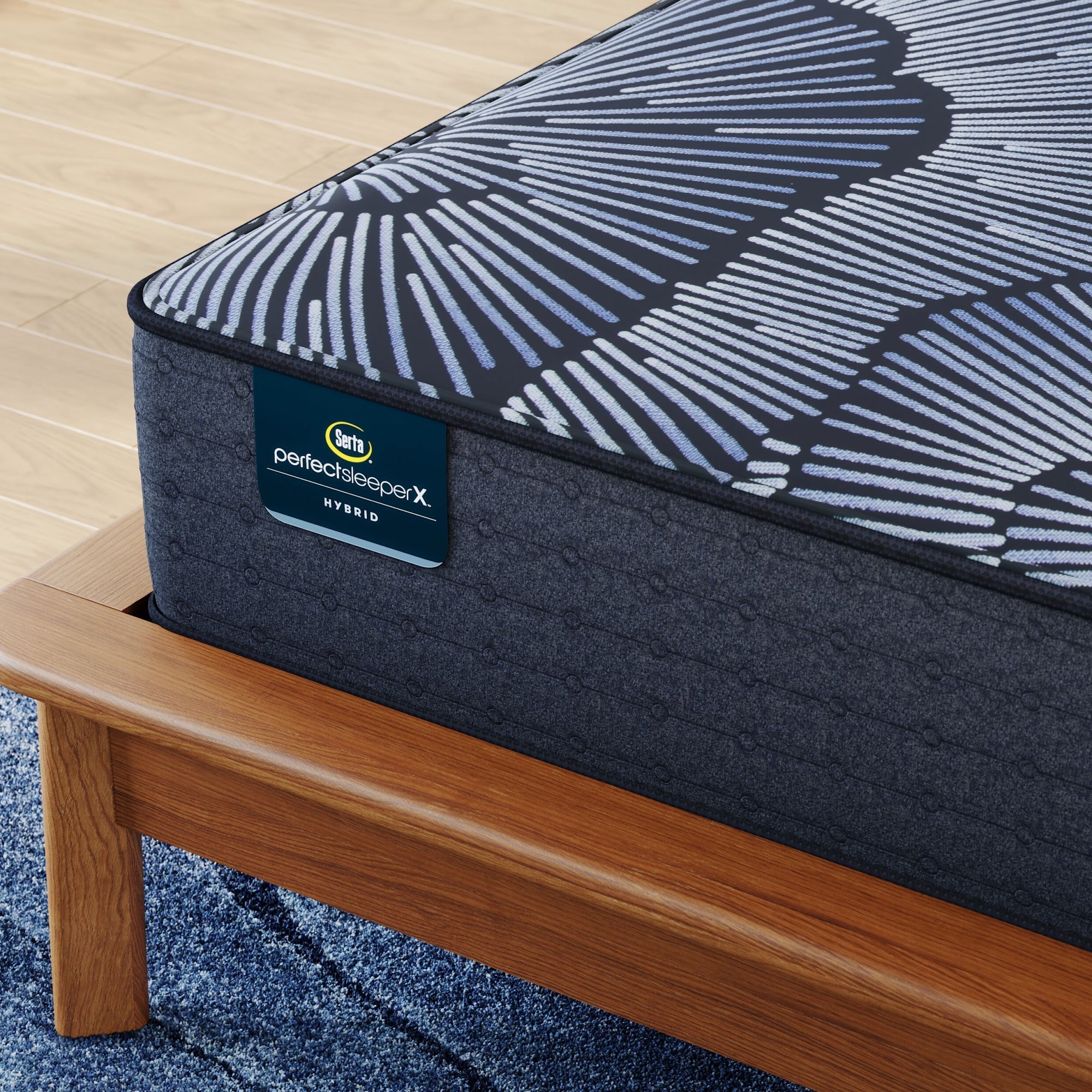 Corner of Perfect Sleeper X Hybrid Kendall Plush Mattress sitting in a brown bedframe || feel: Plush || level: Level 1