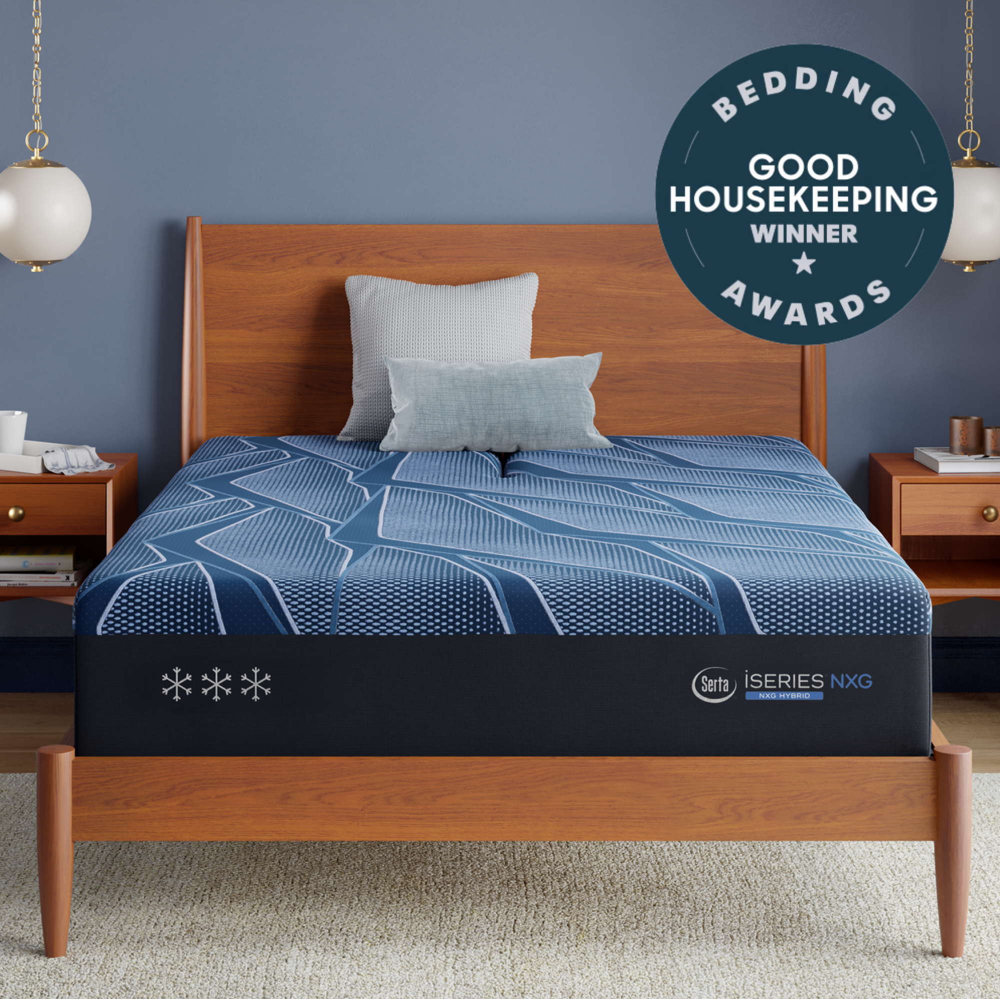 A Blue Serta® iSeries® NXG™ Mattress with a blue pattern and matching pillow set, shown in a styled bedroom with a wooden bed frame, bedside tables, pendant lights, and a circular award badge reading 'Bedding Bedding Good Housekeeping Winner Awards'. The mattress has 'iseries NXG' branding visible on the side.